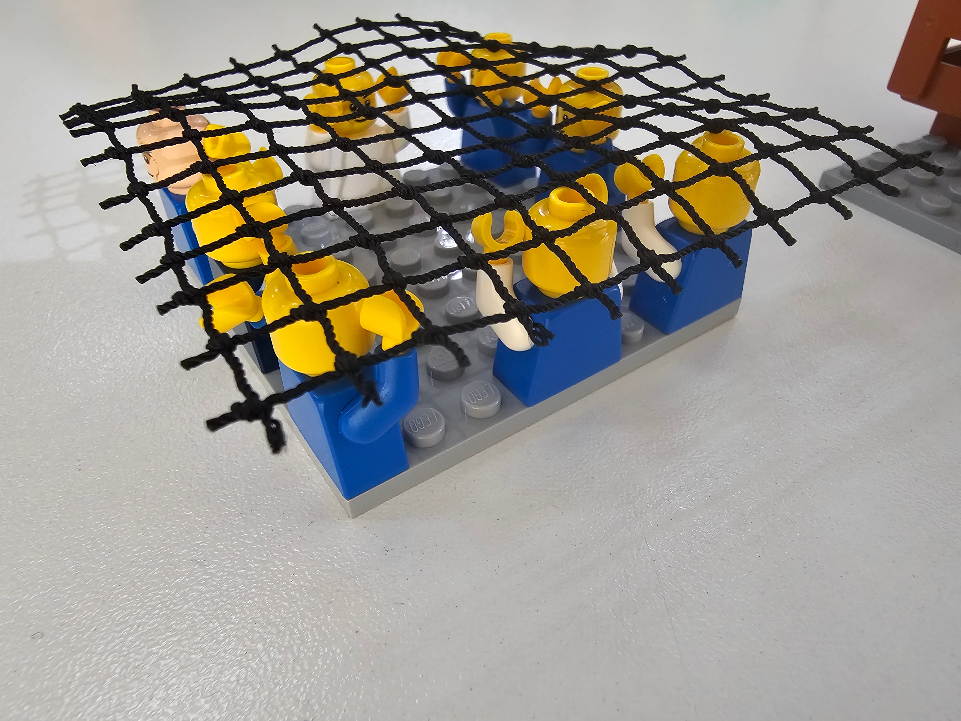Grupo de minifigs sob uma rede simbolizando barreiras e restrições