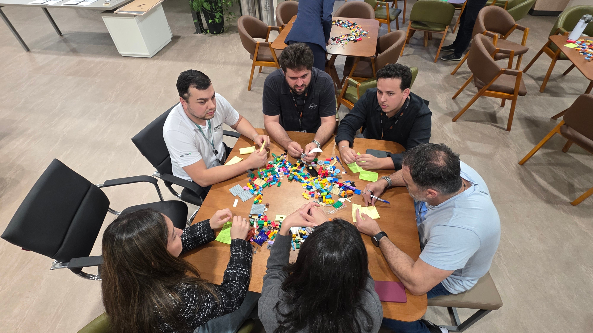 Equipe em volta da mesa construindo modelos LEGO durante sessão LFB